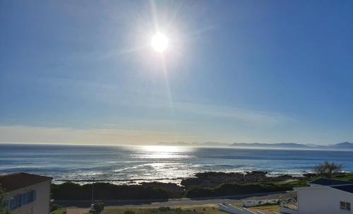 a view of the ocean with the sun in the sky at Sunset Bliss - Gansbaai Seafront Accommodation in Gansbaai