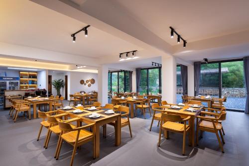 a restaurant with wooden tables and chairs and windows at Hilltop House Resort in Zhangjiajie