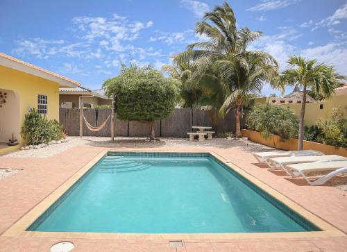 a swimming pool with chairs and a hammock next to a house at Family villa with private pool in peaceful gated resort in Willemstad