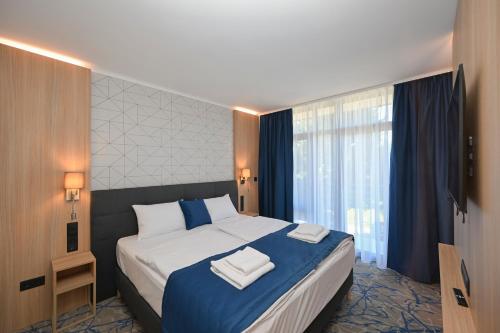a bedroom with a large bed with two towels on it at AquaMed Hotel Harkány in Harkány