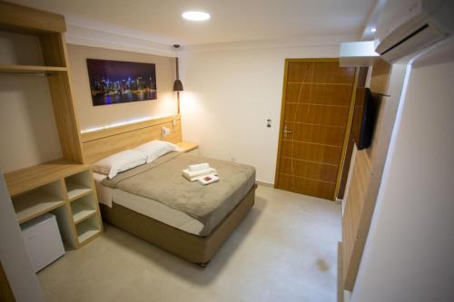 a small bedroom with a bed and a door at Pousada Nascer do Sol in Arraial do Cabo