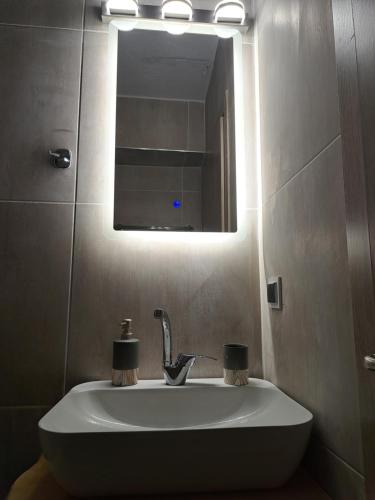 a white sink in a bathroom with a mirror at Azur Infini suites and apartments in Olympiada