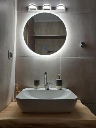a bathroom with a white sink and a mirror at Azur Infini suites and apartments in Olympiada