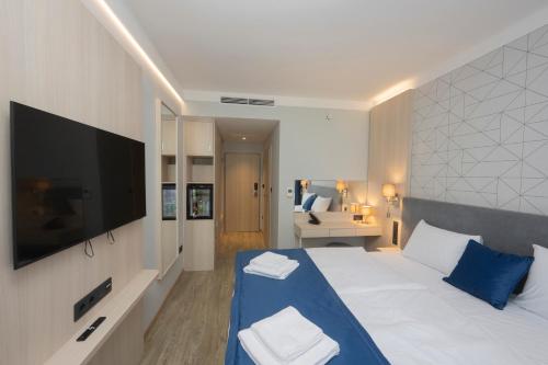 a bedroom with a large white bed with a tv at AquaMed Hotel Harkány in Harkány