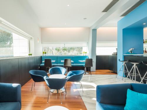 a living room with blue chairs and tables at OPOHOTEL Porto Aeroporto in Maia