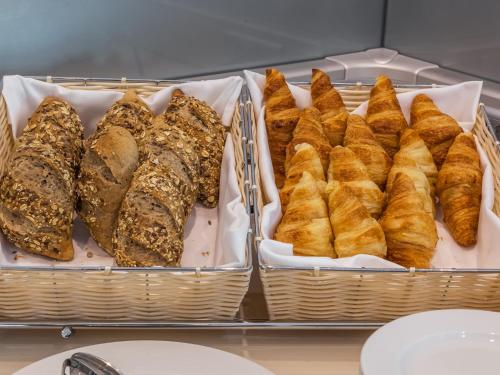 a tray of breads and pastries in baskets at OPOHOTEL Porto Aeroporto in Maia