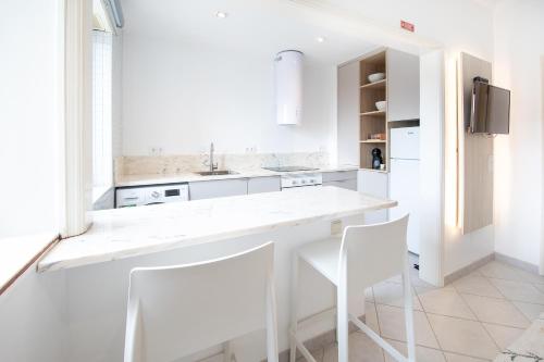 a white kitchen with two white chairs and a counter at One of the Best Views Costa Nova III in Costa Nova