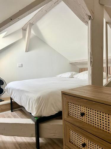 une chambre avec un grand lit blanc dans un grenier dans l'établissement Les toits de Deauville, à Deauville