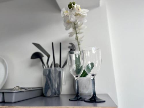 a table with two wine glasses and a vase with flowers at Comfy Apartment - 12 Mins from Gatwick in Ifield