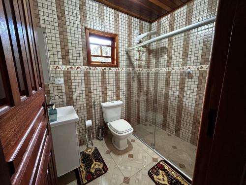 Un pequeño baño con inodoro y ducha. en Chale Sitio Esperança, en Sapucaí-Mirim