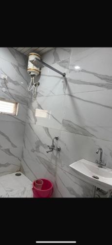 a bathroom with a sink and a white marble wall at Midland Guest House in Pachmarhī