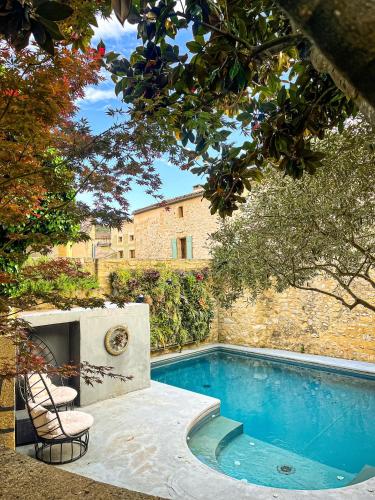 a swimming pool with two chairs next to a building at Le Castellas Hotel & SPA - TERITORIA in Collias