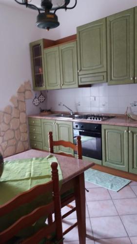 a kitchen with green cabinets and a table with chairs at Appartamento1 in San Teodoro