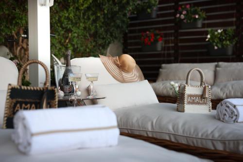 a patio with white couches and a table with wine glasses at Suite Sole Praiano in Praiano
