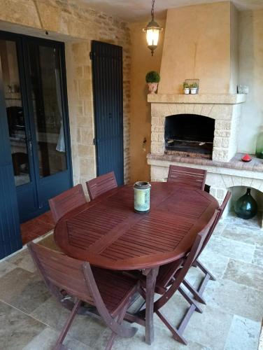 a wooden table and chairs in a room with a fireplace at Maison 6 personnes avec piscine terrain arboré clôturé in Vallabrix
