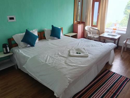 a bedroom with a large white bed with blue pillows at Monal Inn in Mīlam