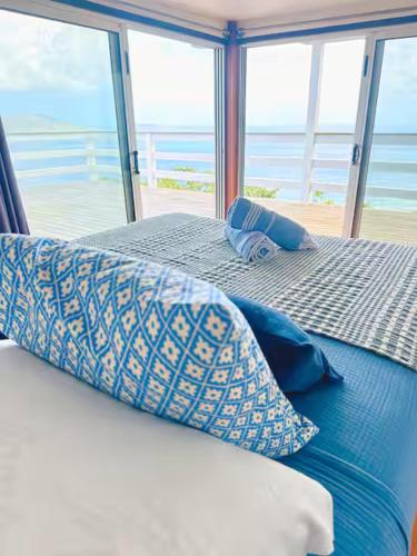 a bed with pillows on it with a view of the ocean at Solace Villa in Little Carrot Bay