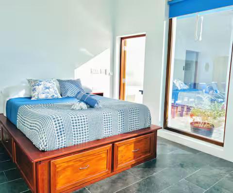 a bedroom with a bed with a dresser and a mirror at Solace Villa in Little Carrot Bay