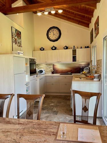 a kitchen with a table and a clock on the wall at Kassopia Serenity Place in Lefkimmi