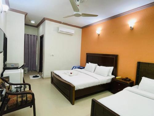 a bedroom with two beds and a ceiling fan at The Host Lodge in Islamabad