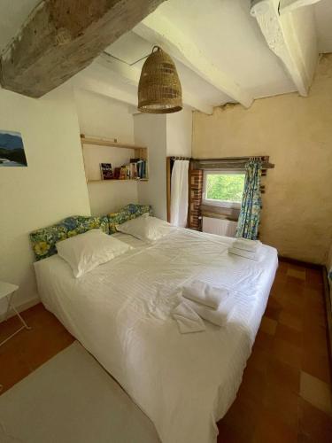 une chambre avec un grand lit blanc avec une fenêtre dans l'établissement Gîte de la Rochejaquelein, à Saint-Fulgent