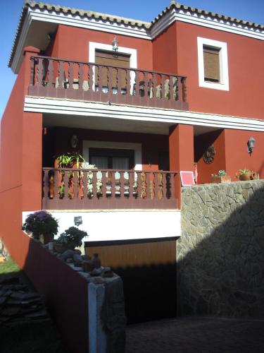 a red and white house with a balcony at La Posada de Menchu in Sanlúcar de Barrameda