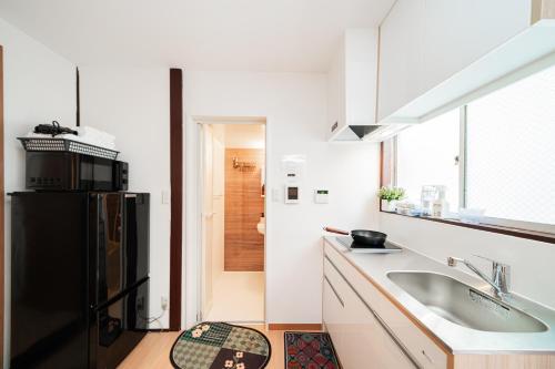 a kitchen with a sink and a black refrigerator at aiki house in Tokyo