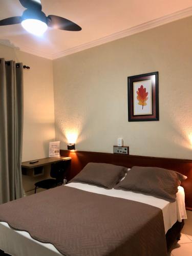 a bedroom with a bed with a desk and a ceiling fan at Hotel de Minas in Caxambu
