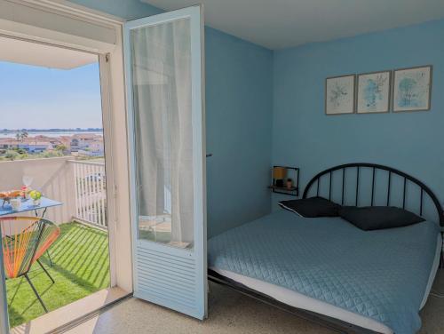 une chambre avec un lit et une porte coulissante en verre dans l'établissement Sol-y-Days Sloop Port Royal 2 chambres et parking terrasse avec vue, au Grau-du-Roi