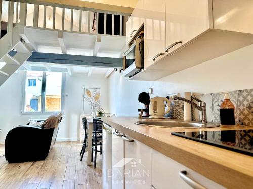 une cuisine avec des armoires blanches et un comptoir dans l'établissement Duplex confortable avec climatisation et cour - ménage et linge inclus, à La Rochelle