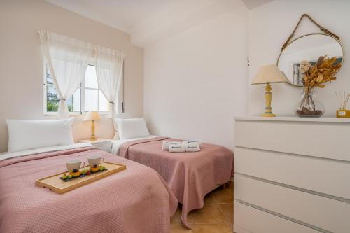 a bedroom with two beds with pink sheets and a tray of fruit at Sunny Flat w/ Balcony near the Sea by HostWise in Albufeira