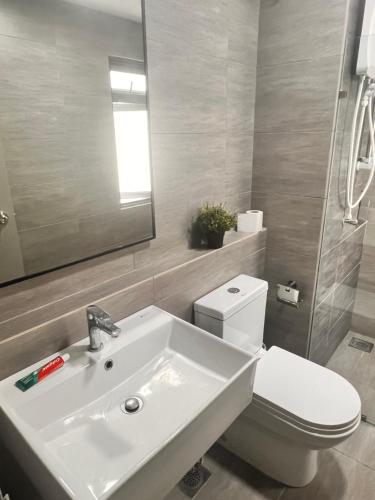 a bathroom with a sink and a toilet and a mirror at Gamuda Cove Homestay in Banting