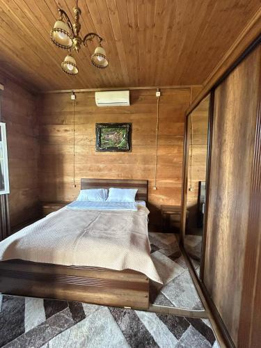 a bedroom with a bed in a wooden wall at Villa Obcha - Whispering Vines Guesthouse in Bagdatʼi