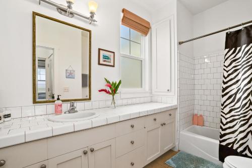 a bathroom with a sink and a tub and a mirror at Tropical Princeville Condo with Private Lanai in Princeville
