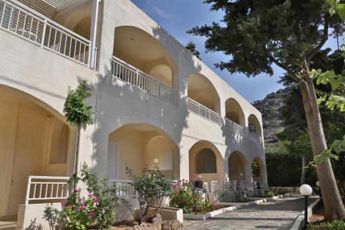 a white building with arches and a tree at Anastasia Hotel Stalis in Stalida
