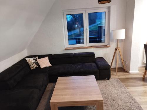 a living room with a black couch and a table at Gemütliche Wohnung auf dem Land in Rosendahl