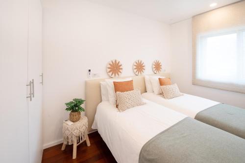 two beds in a room with white walls at Costa Nova Premium Apartment & Pool in Costa Nova