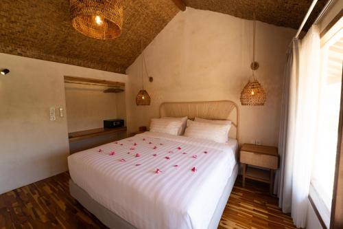 a bedroom with a white bed with red roses on it at Divino Gili Air in Gili Air