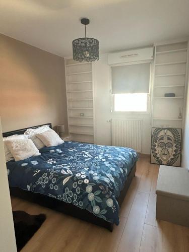 une chambre avec un lit avec une couette bleue et une fenêtre dans l'établissement Le Majolique Nice and Cozy Apartment, à Rouen