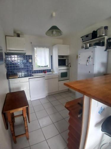- une cuisine avec des appareils blancs, une table et des chaises dans l'établissement maison à 5 min de la plage, à l'Île-Tudy