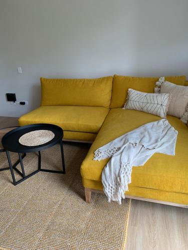 a yellow couch in a living room with a table at Topá House in Medellín