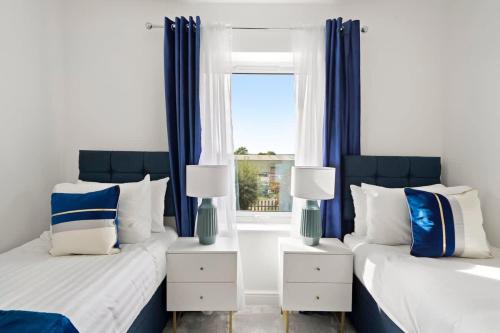 two beds in a room with blue curtains and a window at OFFERS 3 Bed House with Free Parking Ideal for Contractors or Relocation Stays Sittingbourne in Murston