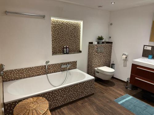 a bathroom with a bath tub and a toilet at Bergisch Resort Josef in Lindlar