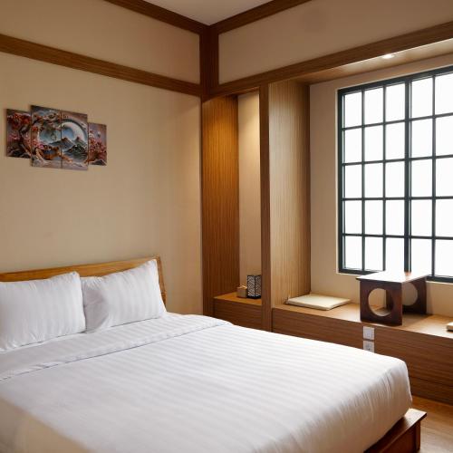 una camera da letto con un letto bianco e una finestra di The Ryokan Semarang a Semarang