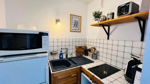une petite cuisine avec un évier et un micro-ondes dans l'établissement L'horizon Océan, studio face mer, à Saint-Jean-de-Monts