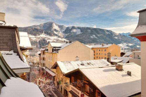 a city with snow covered buildings and mountains in the background at Hotel Grüner Baum in Zell am See