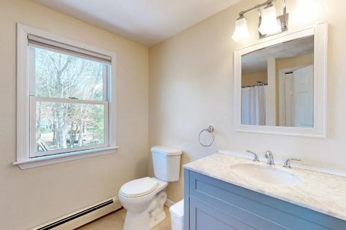 a bathroom with a toilet and a sink and a window at Buttermilk Bliss in Wareham