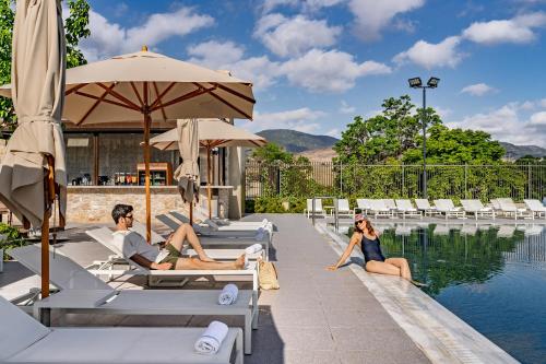 a group of people sitting on lounge chairs by a pool at Ayala by Isrotel Collection in Ayelet HaShahar