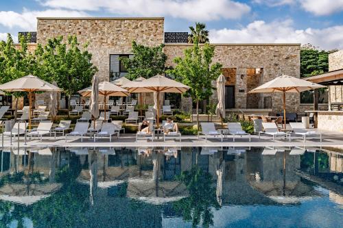 a hotel pool with chairs and umbrellas at Ayala by Isrotel Collection in Ayelet HaShahar