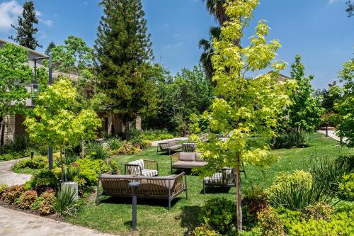 a garden with benches and trees on the grass at Ayala by Isrotel Collection in Ayelet HaShahar